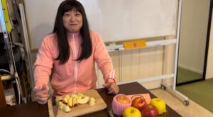 沖縄県那覇市のパーソナルジムでりんごダイエット最終日にトレーナーがカットしたリンゴを前に微笑んでいる様子